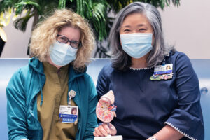 护士Marybeth Bentson和Theresa Pak坐在一起，手里拿着一个肾脏模型。