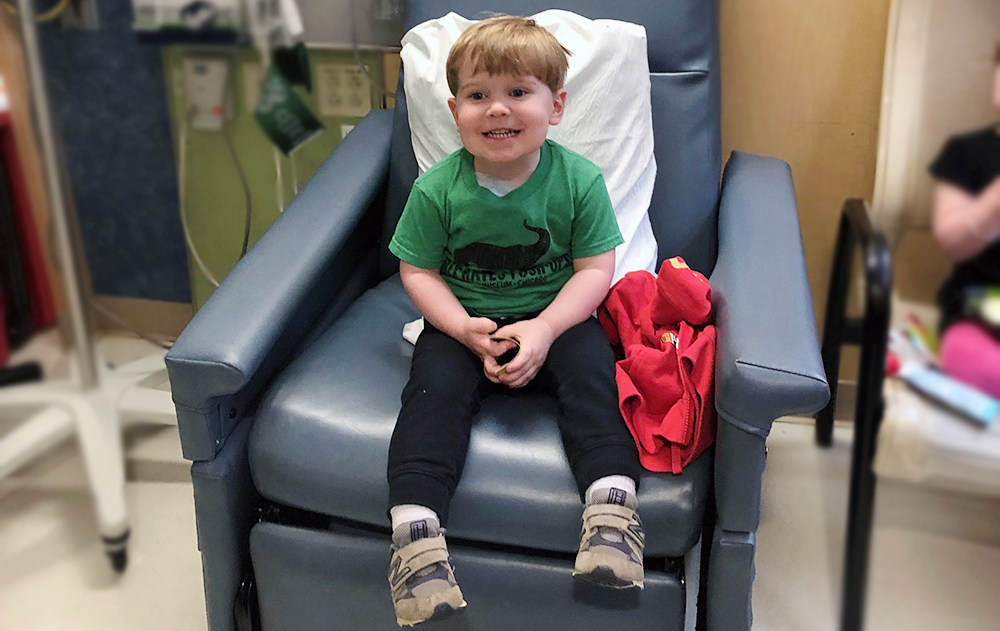 一个男孩坐在波士顿血友病中心的椅子上。