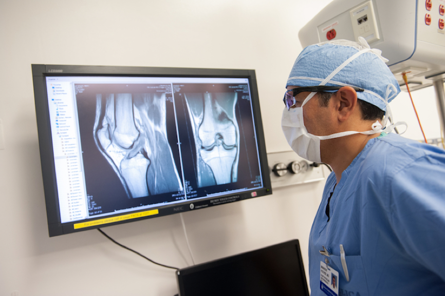 Mininder Kocher，医学博士，运动医学部主任，检查病人膝盖的图像。